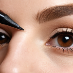 **Pencil Eyeliner Application:** Close-up of a woman's eye as she gently applies a soft, brown pencil eyeliner to her upper lash line. Natural lighting, focus on the precision and ease of application. Soft, everyday makeup look.